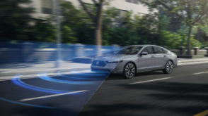 3/4 front view of grey Accord driving on upper-class city street lined with trees. Blue sensor lines and waves emit from the front.