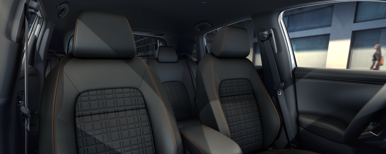 Wide view of front black front seats with orange stitching.