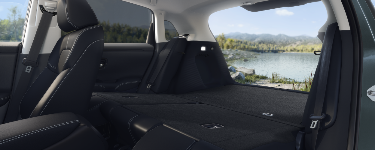 Wide view of a folded-down back seat and open tailgate, showcasing the cargo space in an HR-V. Lake in the background.