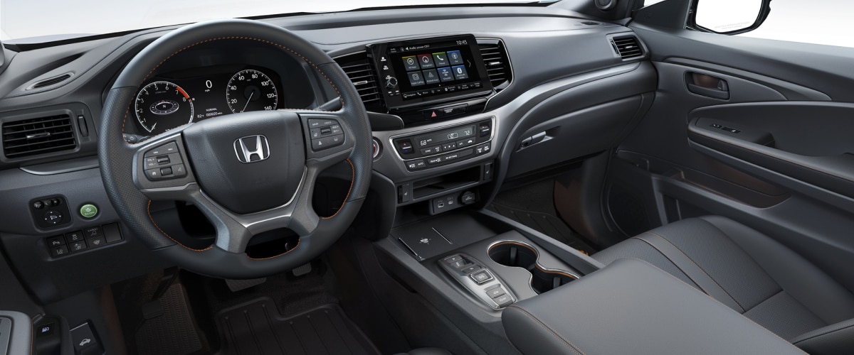 3/4 interior side view of Ridgeline’s front seats and steering wheel, dashboard, and centre console.