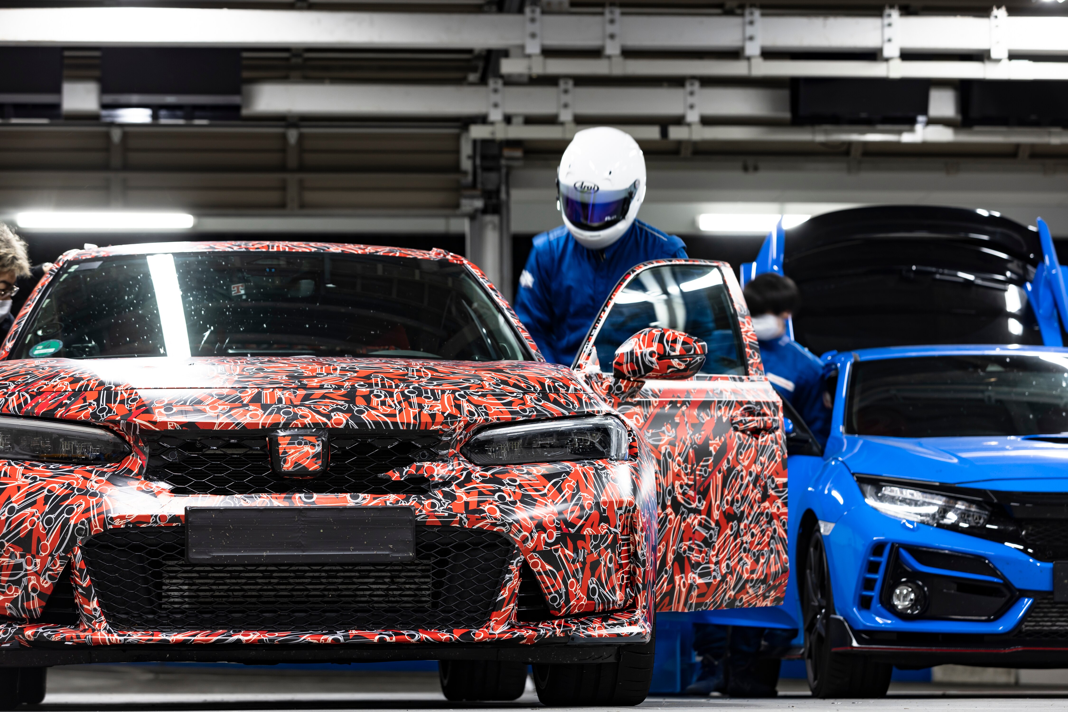 Front view of the 2023 Honda Civic Type R prototype in a garage, with test driver entering the vehicle.