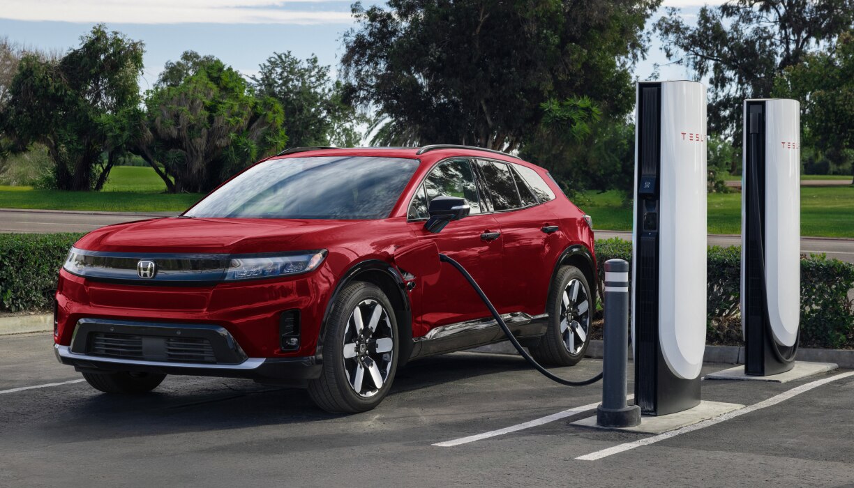 3/4 medium closeup of electric charging stations with cars parked in front. Sun flares give the whole image a warm feel. 