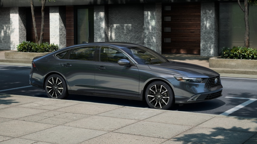 3/4 side view of grey Accord parked curbside on a sunny day in an upscale urban neighbourhood, with wooden townhome garage doors behind it.