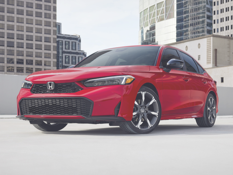 Vue 3/4 avant d’une Civic berline rouge stationnée dans un stationnement sur un toit vide.