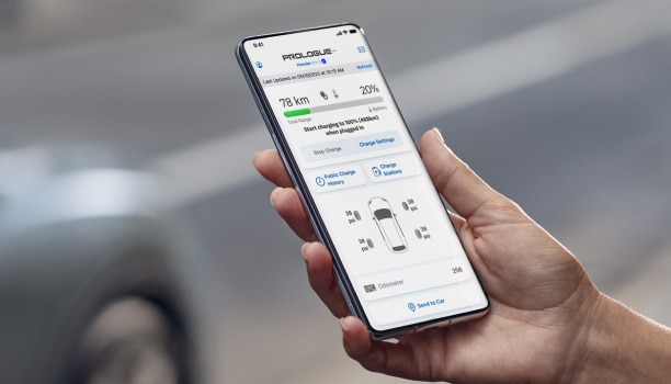 Closeup of a hand holding a smartphone. On the smartphone’s screen is a Prologue diagnostics page. Readouts detail a 20% battery charge and a 78-kilometre driving range.
