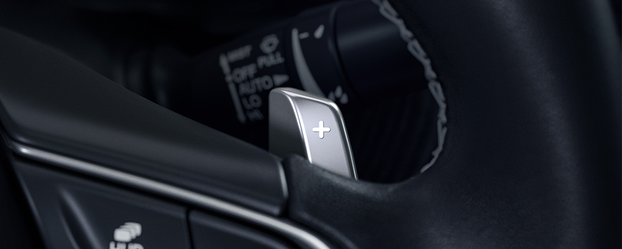 Closeup of paddle shifter and cruise control button on steering wheel.  