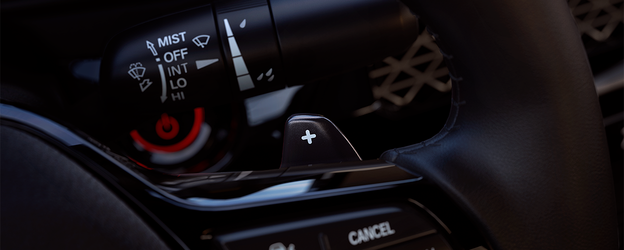 Closeup of the adaptive cruise control’s “increase speed” button on the steering wheel.