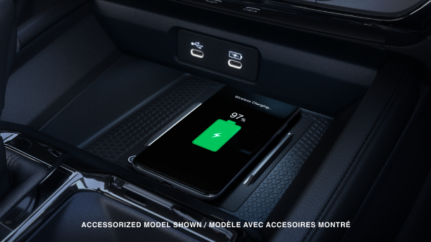 Closeup view of a compatible smartphone charging wirelessly on the charging pad in front of the gear shifter.