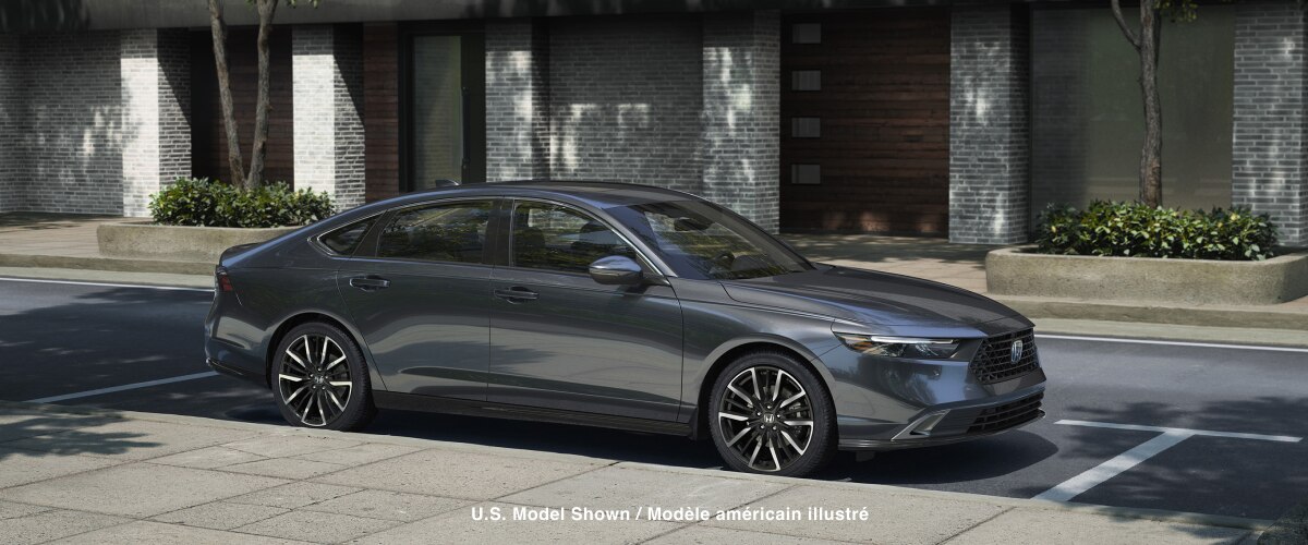Plan de trois quarts avant d’une Accord rouge qui roule vers la caméra dans un virage sur l’autoroute, dans une forêt tempérée, de jour.