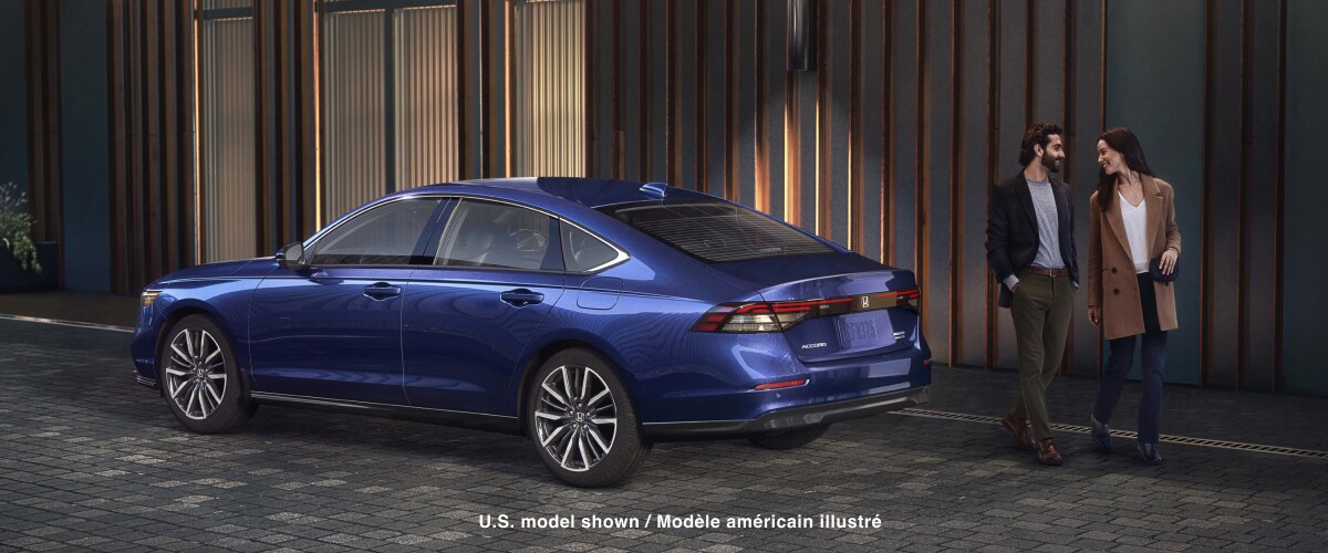 Plan de trois quarts arrière d’une Accord bleue stationnée à l’extérieur d’un bâtiment urbain tendance. Un couple bien habillé s’éloigne de l’Accord. 