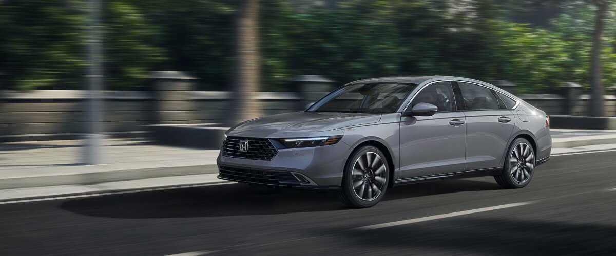 Plan de trois quarts avant d’une Accord grise filant sur une avenue dans un quartier chic.