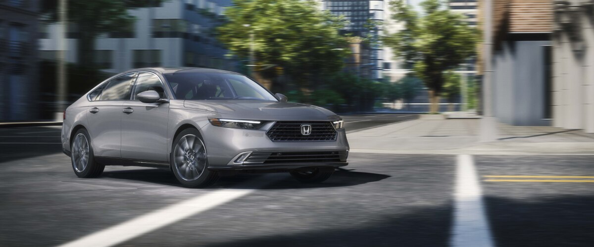 Plan de trois quarts avant d’une Accord grise négociant un virage dans une rue urbaine.