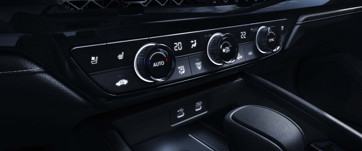 Gros plan de trois quarts des commandes de climatisation sur la console centrale.