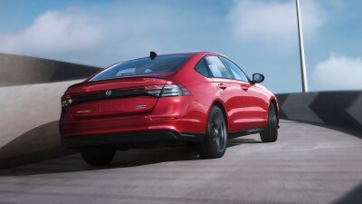 Plan de trois quarts arrière d’une Accord rouge remontant la rampe d’un stationnement à étages extérieur.