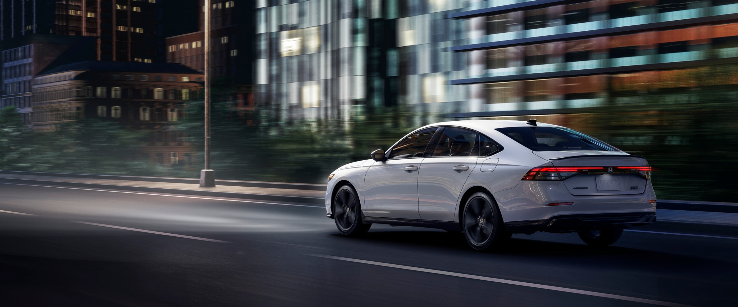 Vue 3/4 arrière d’une Accord blanche circulant dans une rue en ville.