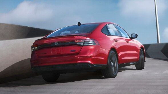 Vue 3/4 arrière d’une Accord rouge montant une bretelle sous un ciel bleu clair.