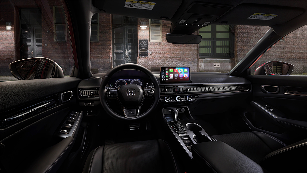 Interior panoramic view of the steering wheel and dashboard on a Hatchback parked in front of brick wall in an old warehouse district.