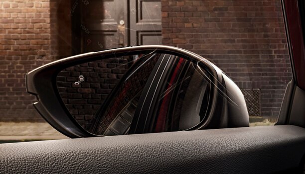 Gros plan du rétroviseur intérieur avec réflexion d’un véhicule et témoin d’angle mort illuminé. 