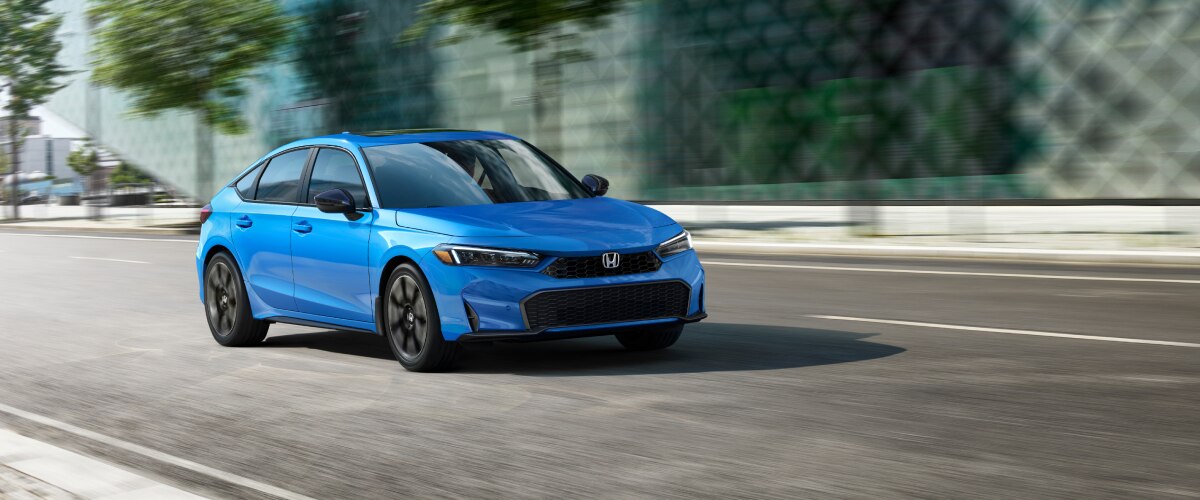 Plan avant d’une Civic à hayon bleue circulant en ville. 