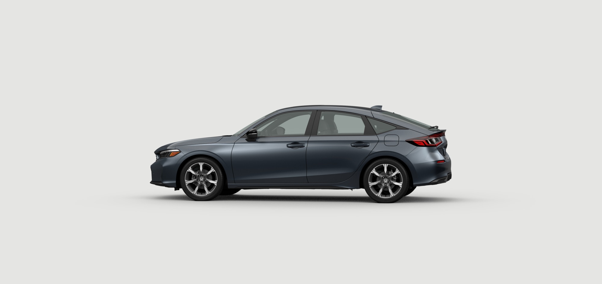 Side driver-side view of 2025 Civic Hatchback Sport Touring Hybrid  in Meteoroid Grey Metallic colour on white space. 