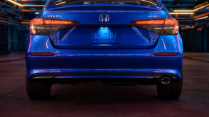 Rear view of a parked blue Honda Civic Sedan in a dark warehouse-like space.