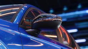 Close up of door mirror on a blue Civic Sedan in a dark warehouse-like space.