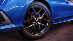 Close up of the front wheel on a parked blue Honda Civic Sedan in a dark warehouse-like space.