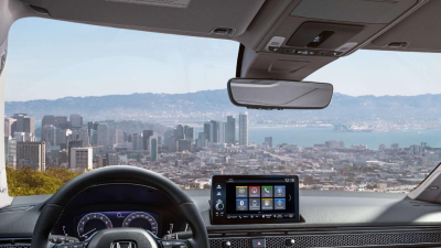 Panoramic view through the windshield, overlooking a waterfront cityscape. 