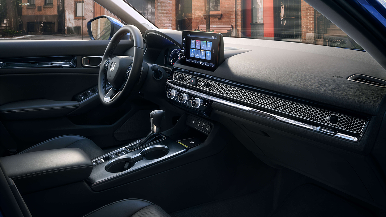 Side view of front row, passenger side, showing dashboard, centre console, and steering wheel.