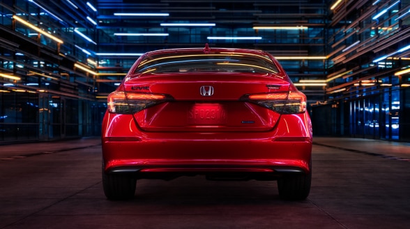 Rear view of a parked red Civic Sedan in a dark warehouse-like space.