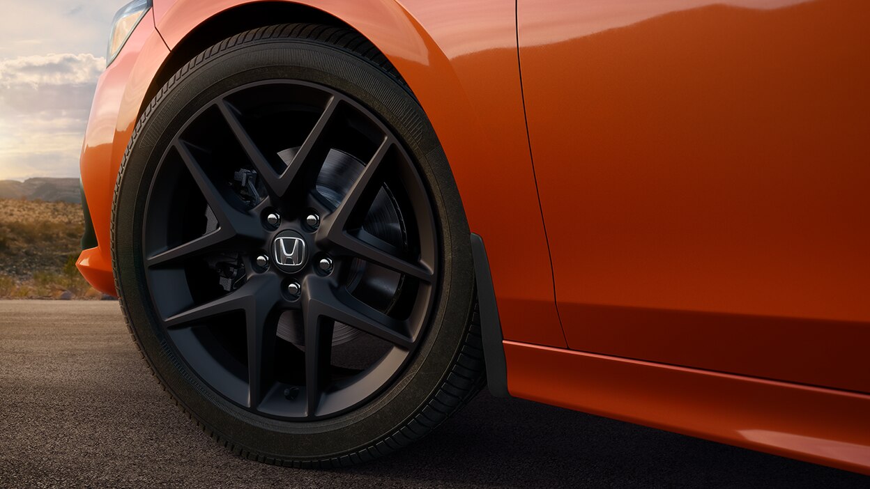 Closeup of black wheel on orange Civic Si.