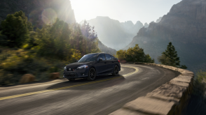 3/4 front side view of black Civic Si taking a turn on a mountain highway. 