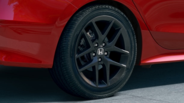 Closeup of black wheel on red Civic Si.