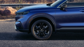 Sideview of the front of a blueHonda CR-V, highlighting its black aluminum-alloy wheel. 