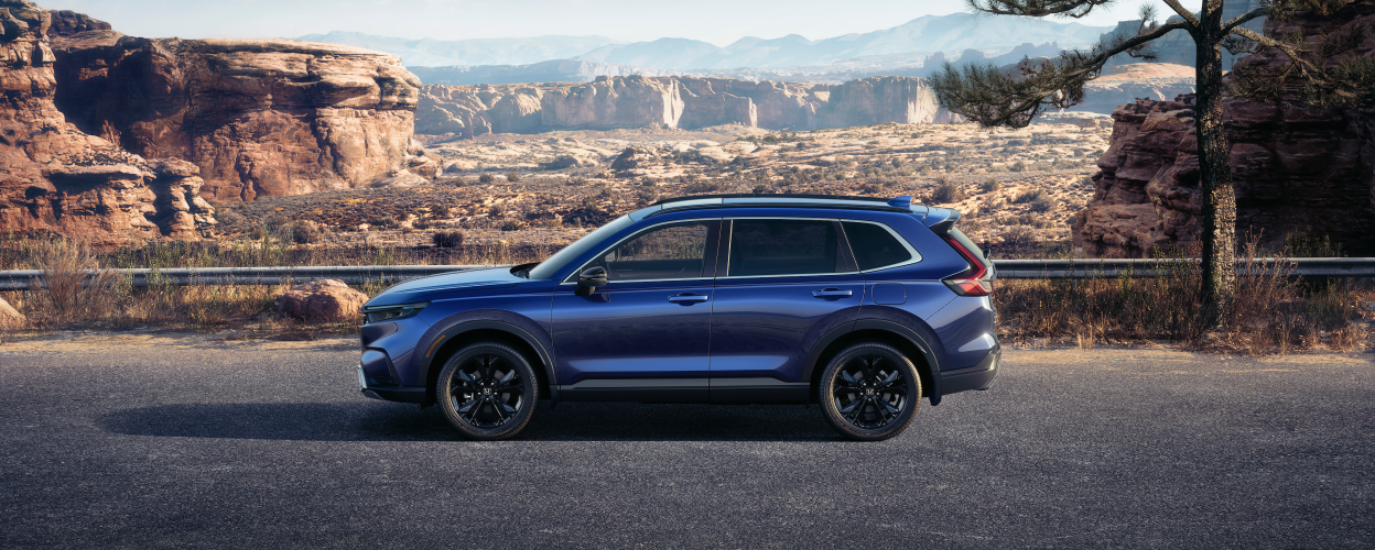 Sideview of a blue 2023 CR-V parked in the desert. Desert backdrop.