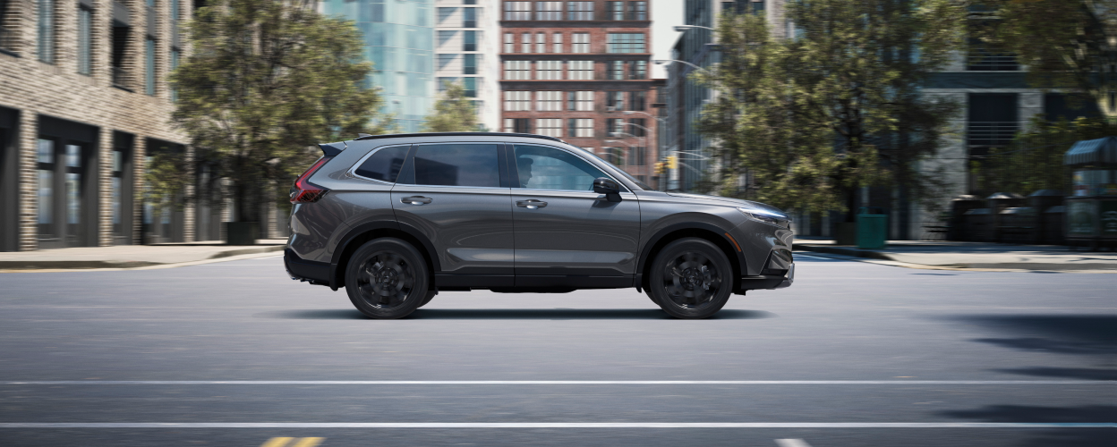 Sideview of grey 2023 CR-V driving in the city.