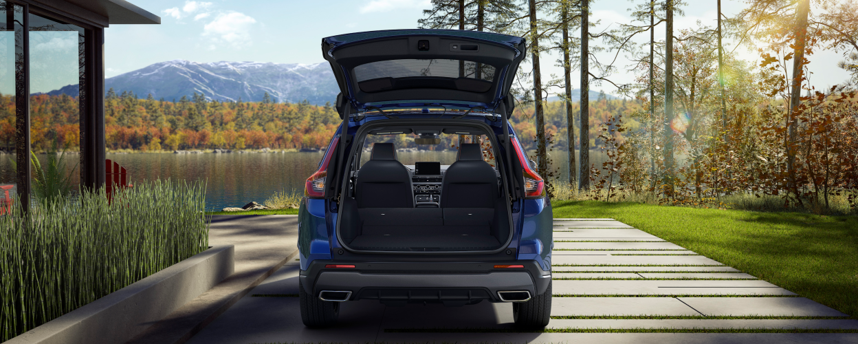 Rear view of open tailgate on a parked blue CR-V; lake and fall-coloured trees as backdrop.