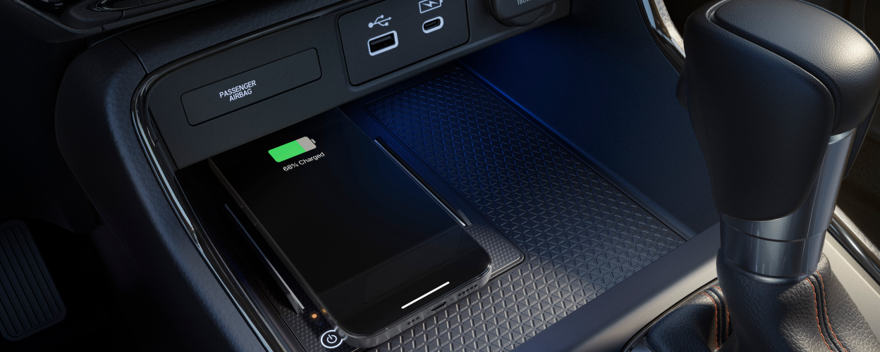 Closeup of smartphone charging on wireless charging pad in centre console.