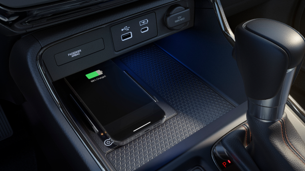 Closeup of smartphone charging on wireless charging pad in centre console. 