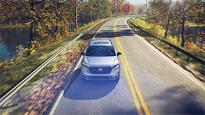 3/4 bird’s eye front view of grey CR-V driving on lakeside highway. Blue sensor lines emit from the front.