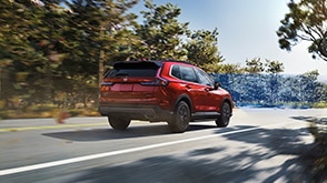 3/4 rear view of red CR-V driving on forest highway. Blue sensor lines emit from the front.