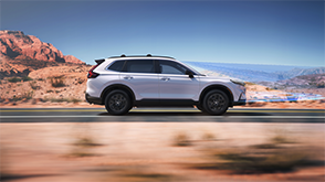 Sideview of white CR-V driving on desert highway. Blue sensor lines and waves emit from the front. 