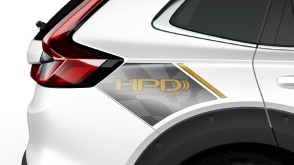 Closeup of back fender on a white HPD CR-V on white space. The grey and gold-lettered decal reads: HPD. 
