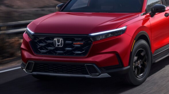 Closeup of front of a red CR-V on a mountain highway.