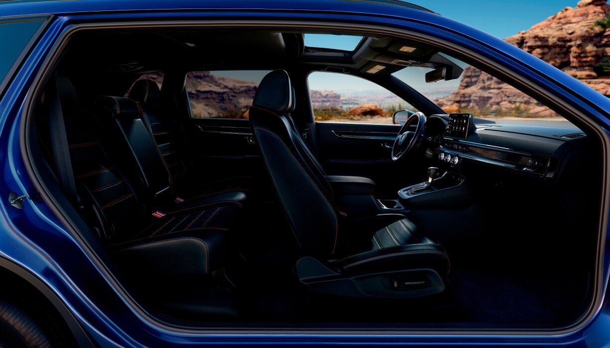 Panoramic sideview of the front and rear seats in a blue CR-V parked in the desert. 