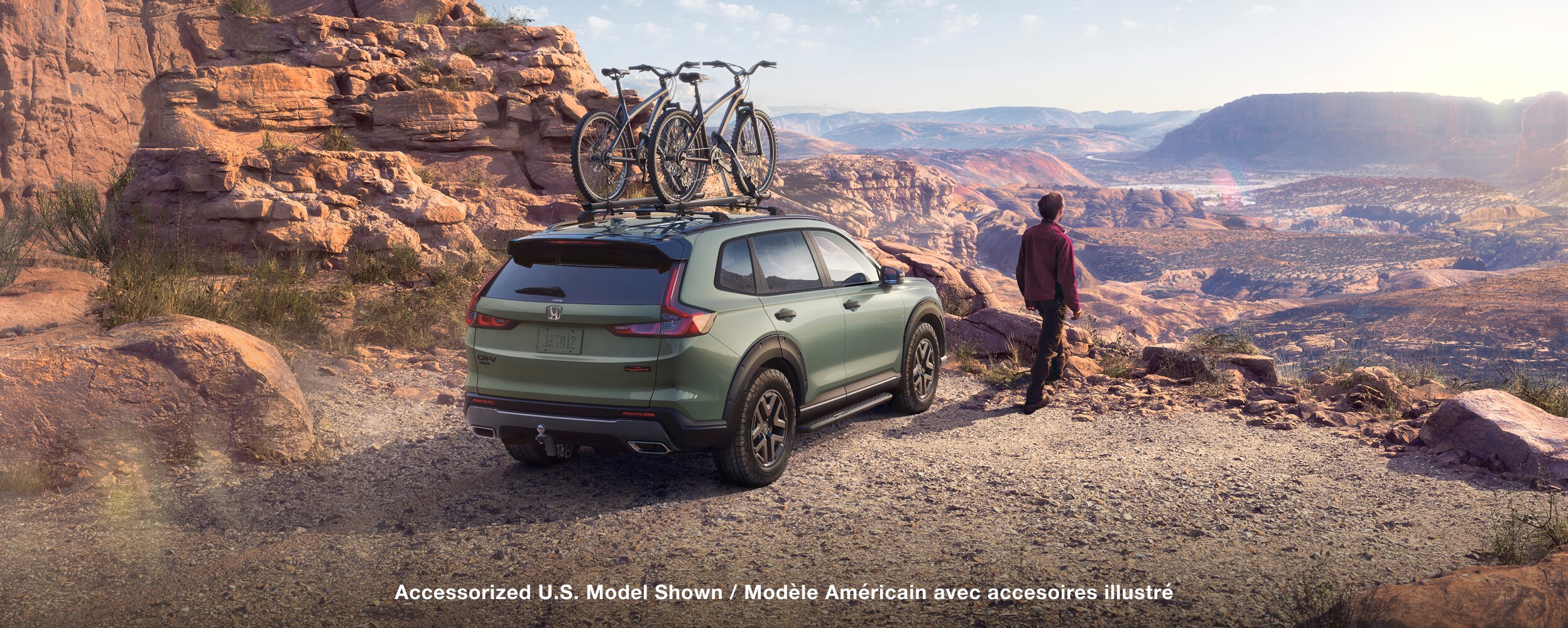 Wide side view of parked green CR-V overlooking desert canyons and mountains.