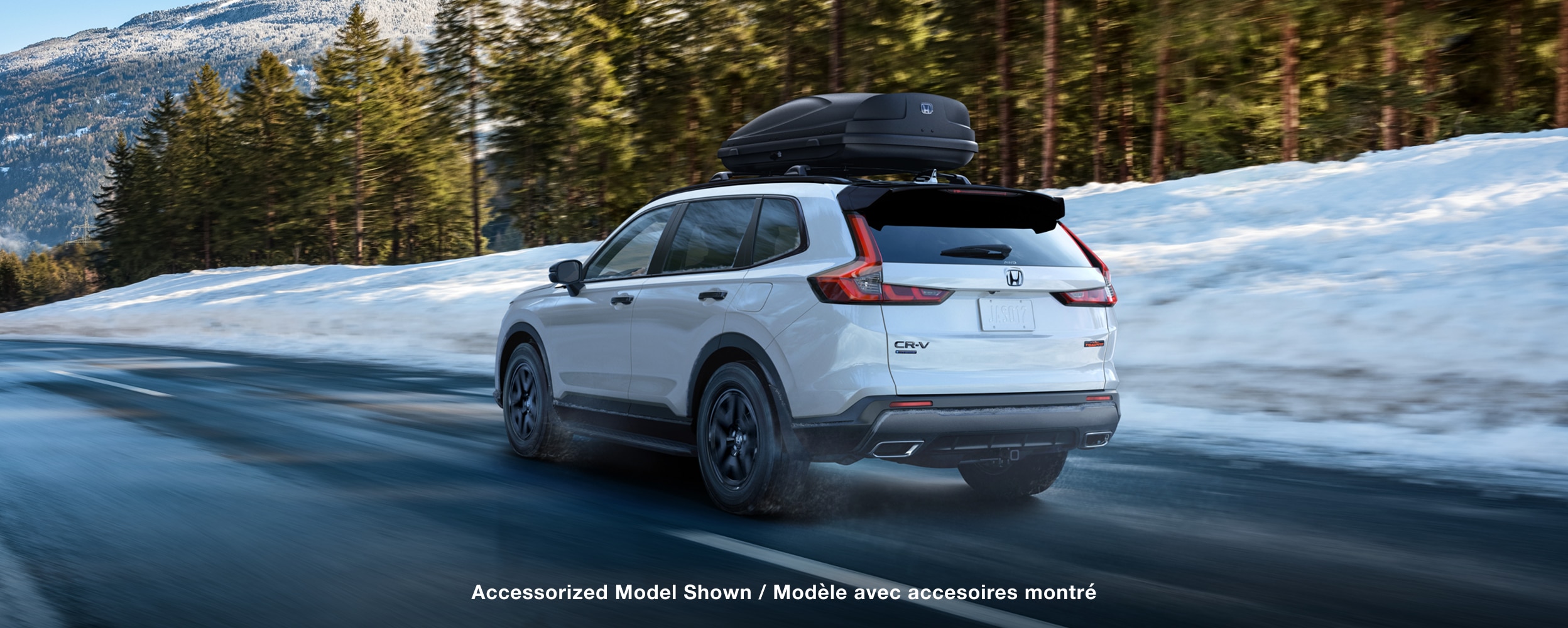 Rear-view of white CR-V driving on a road in a snowy environment.