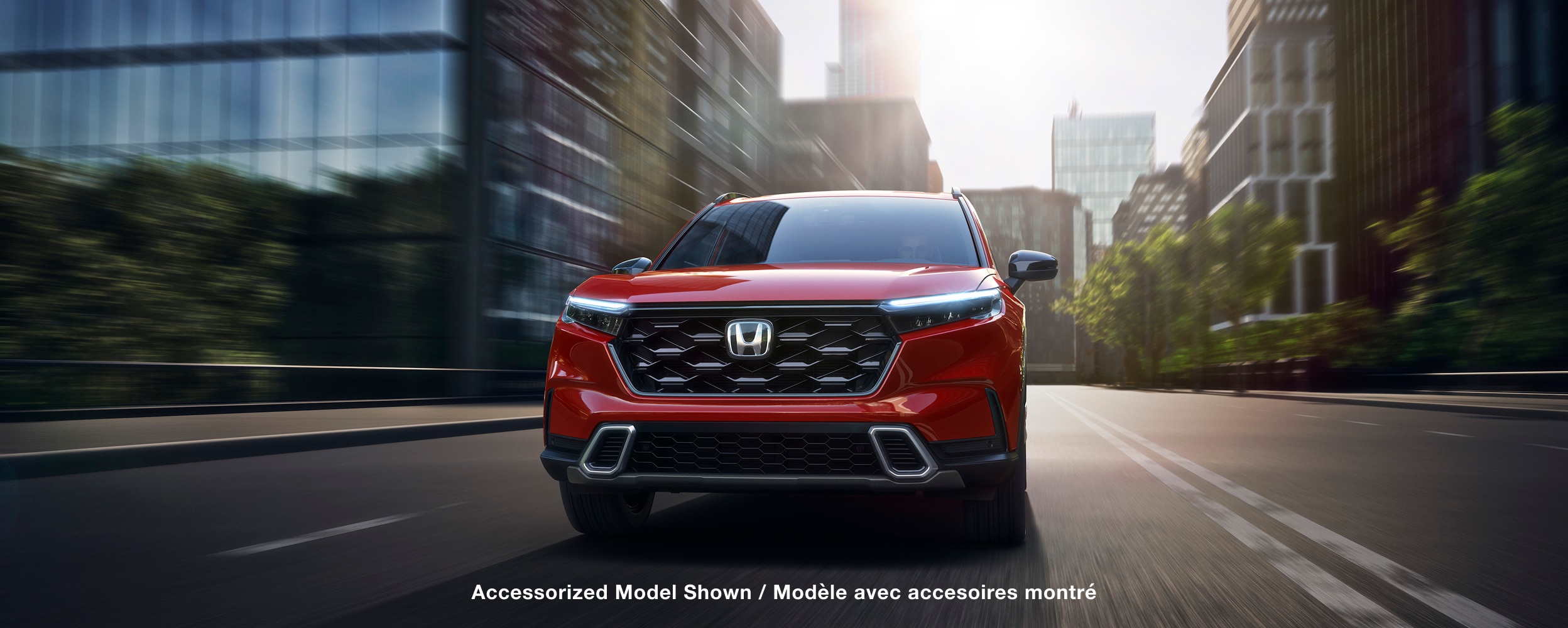 Front view of red CR-V driving on a city street.