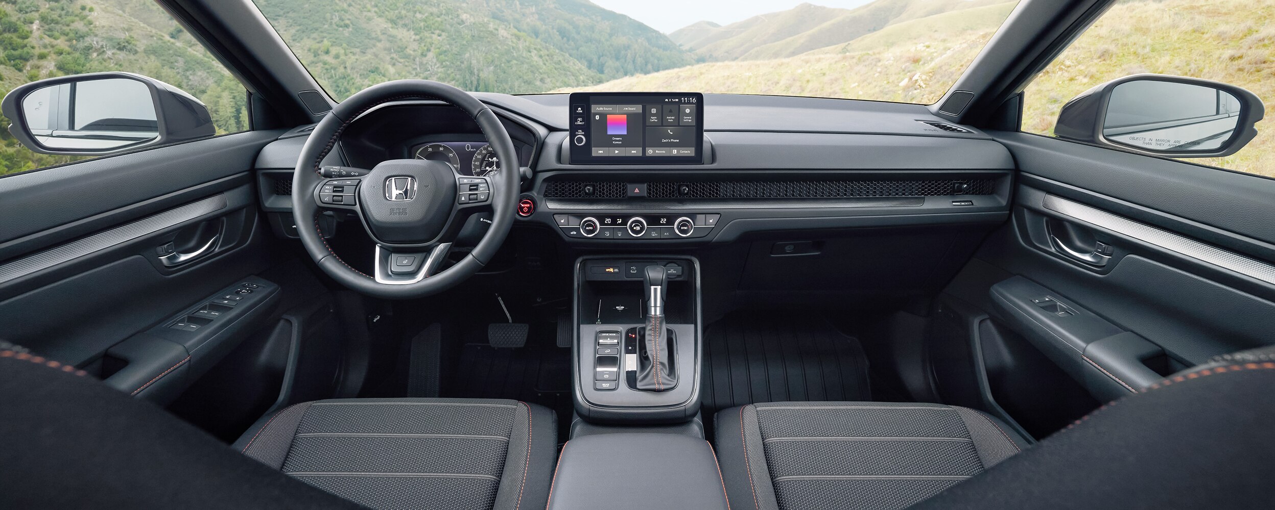 Panoramic interior view from the bakseat with wide open space visible though the windshield. 