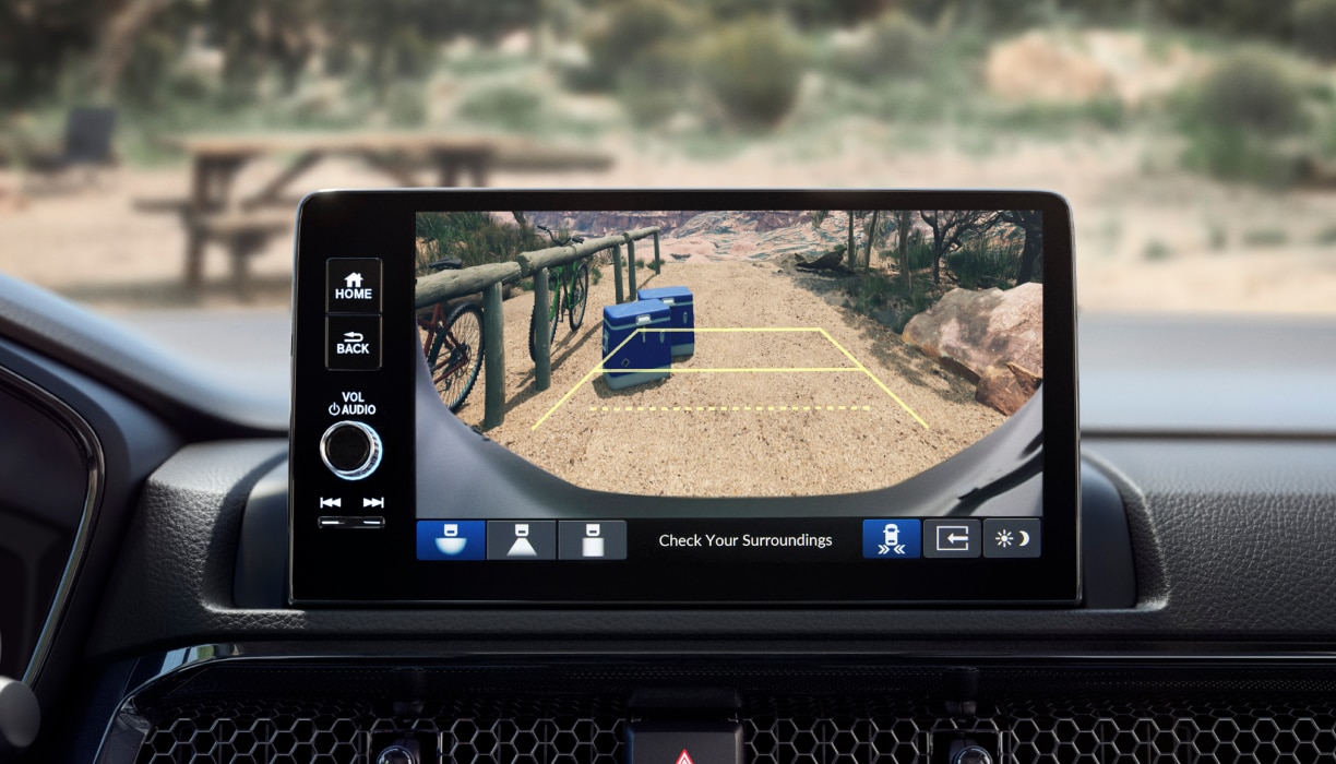 Closeup of touchscreen display. Through the windsheild there is a picnic ground.